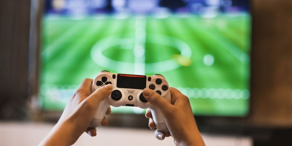 a playstation controller with a sports game on the TV
